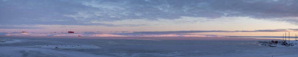 Sea, buildings and snow, with a colourful sky