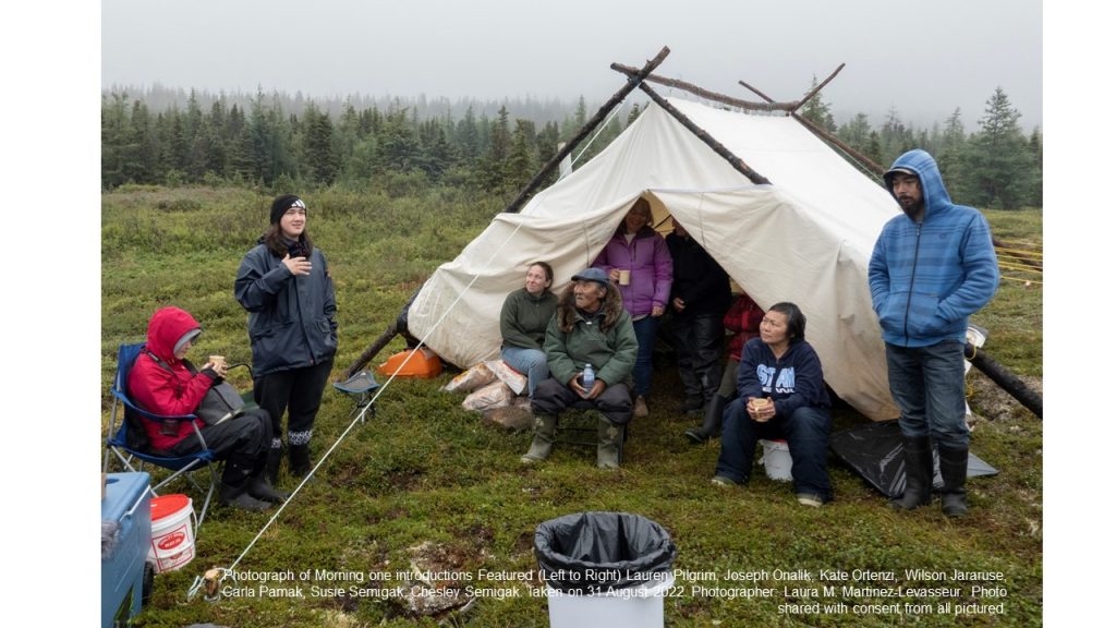 people sitting in front of a tent having a discussion under cloudy and wet skies