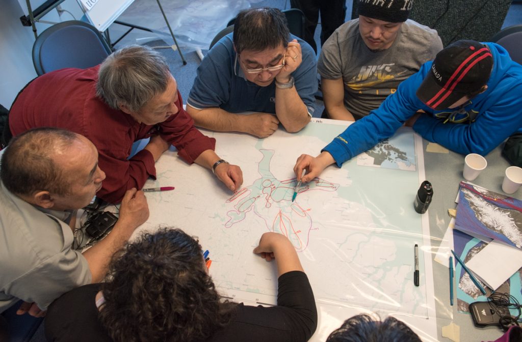 A team of people sitting aroun a table looking at a map.