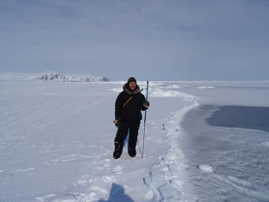 A person walking in the snow near the flow edge to fish and hunt