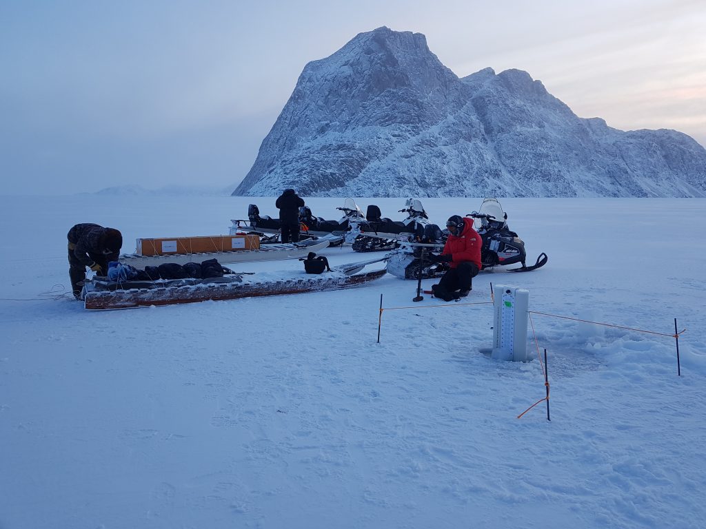 People deploying instuments in the snow with rocks in background.